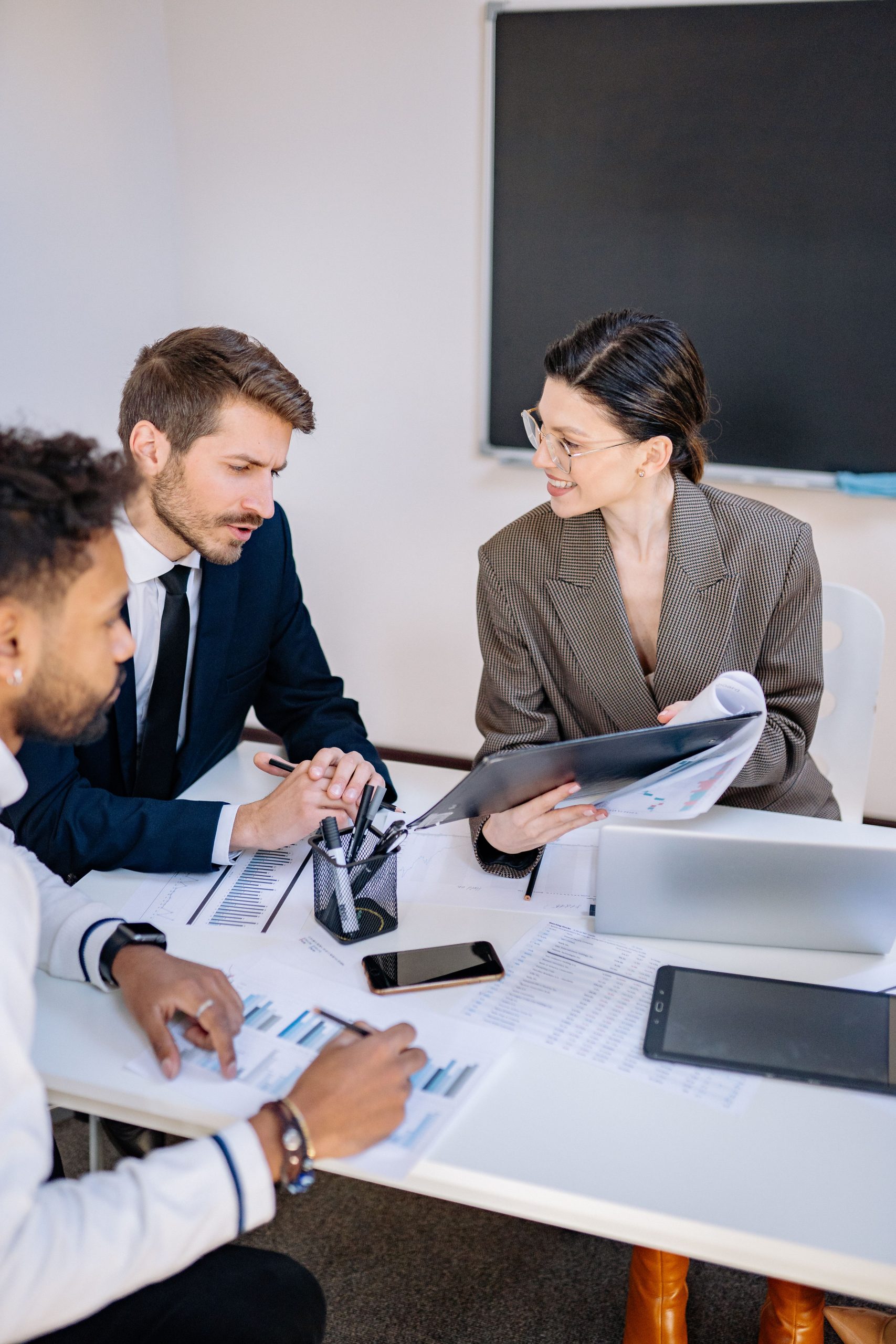 Three professionals engaged in a productive office meeting sharing ideas and discussing strategies.